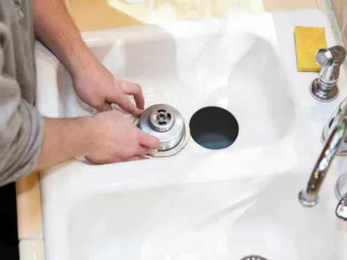 Man installing garbage disposal in home.