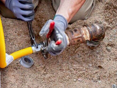 A Plumber hooking up a temporary gas line to a propane tank