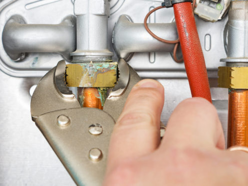 Plumber repairing a leaking gas boiler of a heating home system. Service household gas appliances, concept.