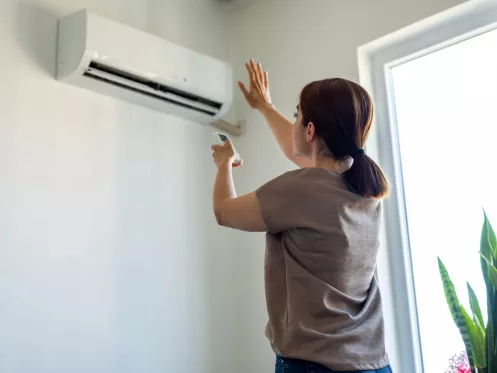 Woman turning on air conditioner